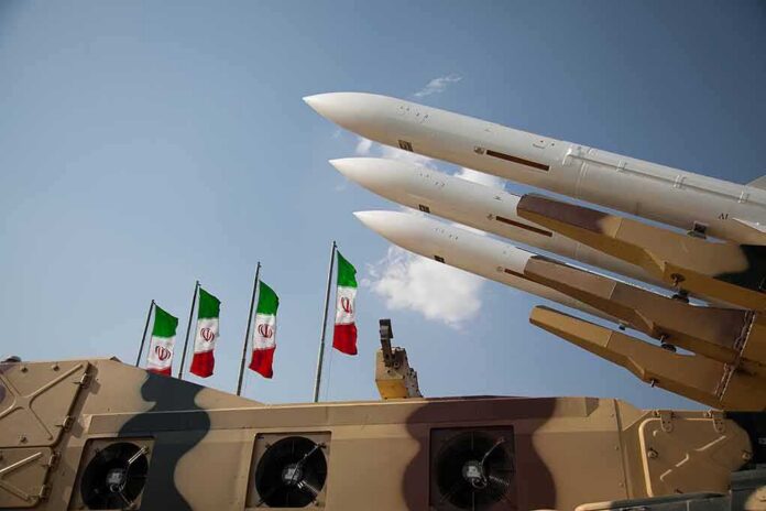 shutterstock_1621002841 Missile launchers on a military vehicle with flags in the background