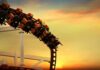 roller coaster train rounding a curve at sunset