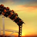 roller coaster train rounding a curve at sunset