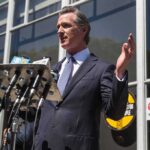 man in suit speaking at outdoor press conference