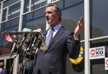 man in suit speaking at outdoor press conference