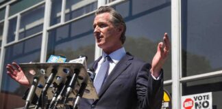 man in suit speaking at outdoor press conference