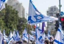 Election Showdown Spills Onto Israel’s Streets Israeli flags waved at a street demonstration