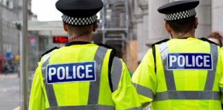 Two police officers in high-visibility jackets walking on a city street
