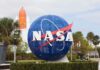 NASA globe sign at visitor center with space shuttle booster in background
