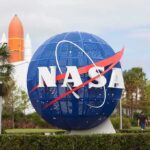 NASA globe sign at visitor center with space shuttle booster in background