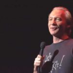 comedian holding a microphone on stage