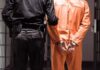 Hollywood Double-Murder: Death Off The Table Prisoner in orange jumpsuit handcuffed with guard standing beside