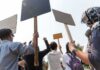 Group of people holding protest signs outdoors