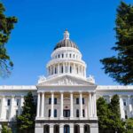 State capitol building with white dome and columns framed by trees