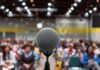 “I Hit You” Sparks A Campus Firestorm Microphone on stage facing a blurred audience