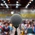 Microphone on stage facing a blurred audience