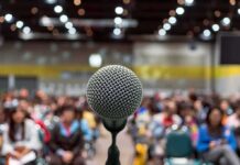 Microphone on stage facing a blurred audience