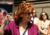 Graphic Jab Airs – Trump Name Invoked Woman in sunglasses holding a plastic cup and smiling outdoors