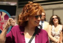 Graphic Jab Airs – Trump Name Invoked Woman in sunglasses holding a plastic cup and smiling outdoors