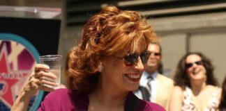 Woman in sunglasses holding a plastic cup and smiling outdoors