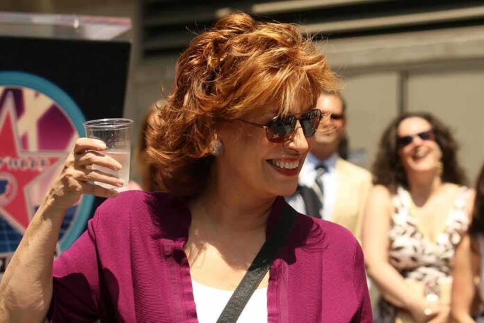 Woman in sunglasses holding a plastic cup and smiling outdoors