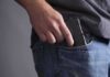 Hand placing a handgun into a jeans pocket
