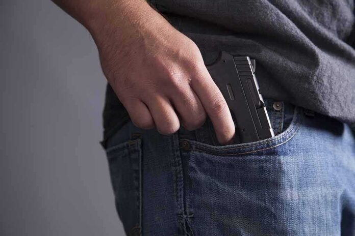 shutterstock_113470597 Hand placing a handgun into a jeans pocket