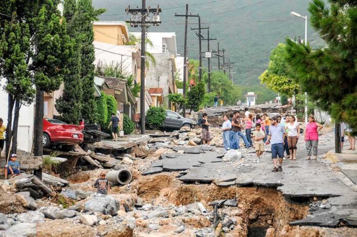 Residents walk along a heavily damaged street after a disaster