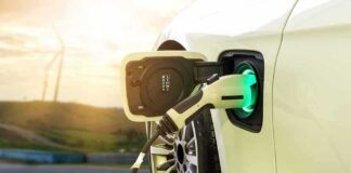 Electric car charging with a plugged-in connector at sunset