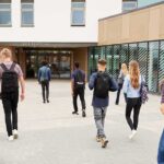Students with backpacks walking toward a school entrance