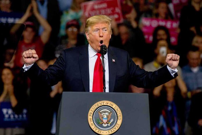 politician speaking at a rally with raised fists behind a podium