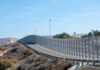 Tall metal border fence curving through arid landscape