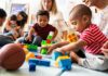 Karyn Polito with toddlers building blocks on a play mat