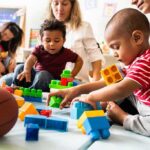Karyn Polito with toddlers building blocks on a play mat