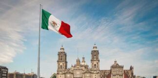 Mexican flag over a historic cathedral in a large city square