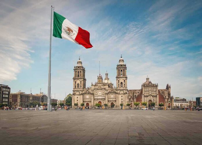 Mexican flag over a historic cathedral in a large city square