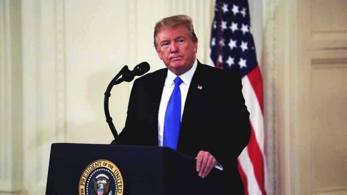 shutterstock_1326218579 man at podium with microphone and US flag