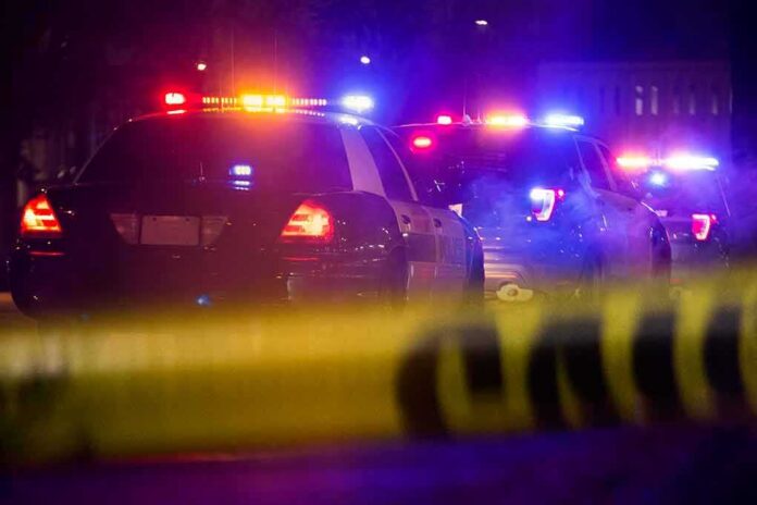 shutterstock_1349511497 Police cars with flashing lights behind yellow caution tape at night