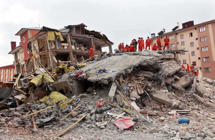 shutterstock_148947701-1 Rescue workers in orange uniforms on a collapsed building site after an earthquake