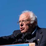 Bernie Sanders speaking at a podium outdoors