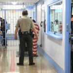Corrections officers escort an inmate in a jail hallway
