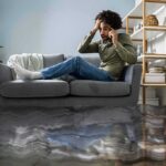 Man on couch calling for help during home flooding