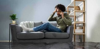 Man on couch calling for help during home flooding