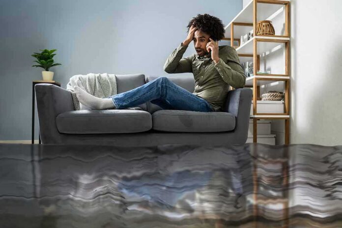 Man on couch calling for help during home flooding