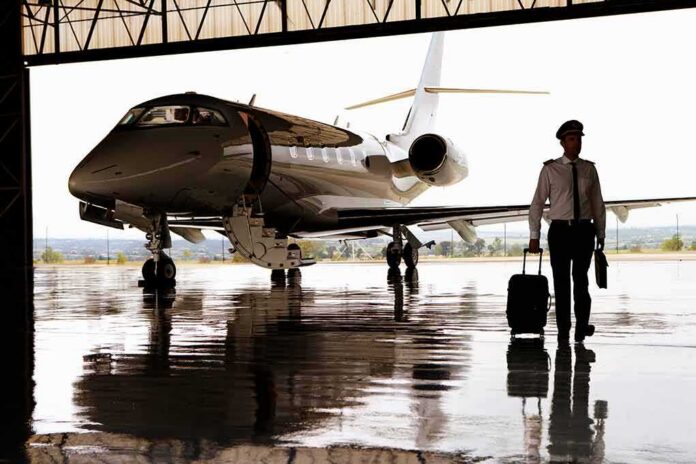 Pilot walking with suitcase beside private jet in hangar