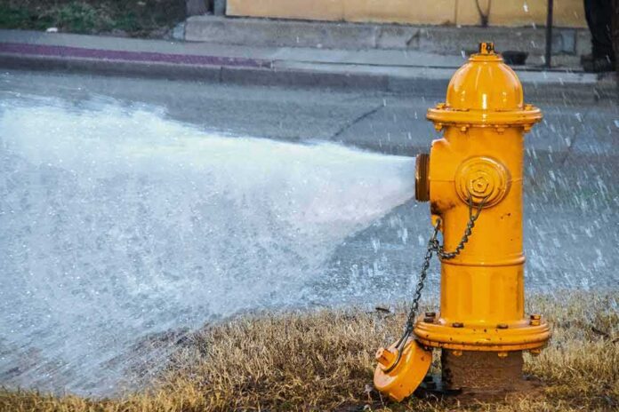 shutterstock_1650298723 Yellow fire hydrant gushing water onto a street