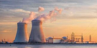 Nuclear power plant with cooling towers emitting steam at sunset
