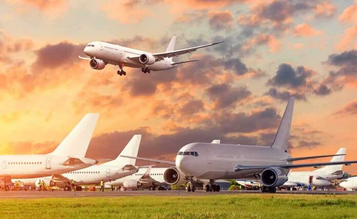 Passenger jets on airport tarmac with one aircraft landing at sunset