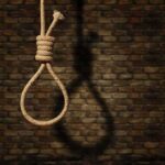 Rope noose hanging against a brick wall