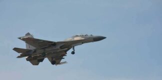 Military fighter jet in flight with landing gear down
