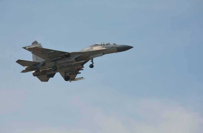 Military fighter jet in flight with landing gear down