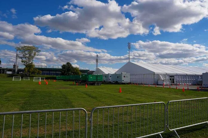 shutterstock_2216173395-1 Temporary white tents and equipment on a grassy field with traffic cones and metal barriers