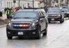 black SUVs with flashing lights driving in a motorcade