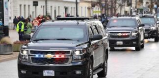 black SUVs with flashing lights driving in a motorcade